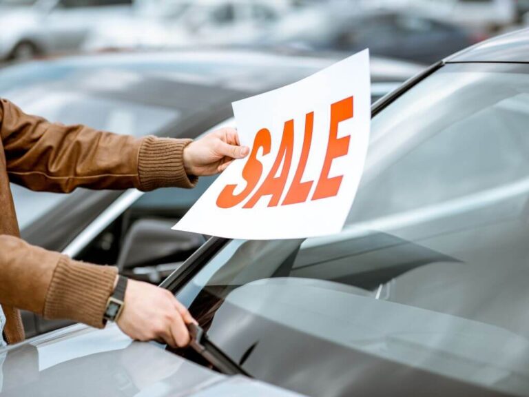 Placing a for sale sign on a car window showing preparation for selling.