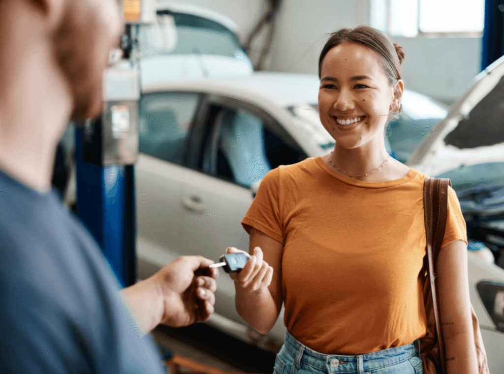 A woman confidently handing her car keys to a workshop mechanic for routine maintenance under her Service Plan.