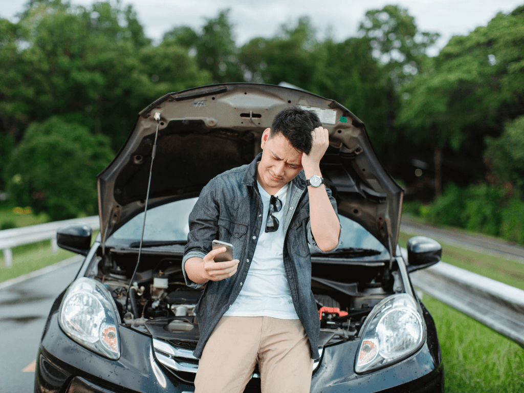 A man stands beside a car with its hood open, illustrating the importance of choosing the right types of car cover for vehicle protection.